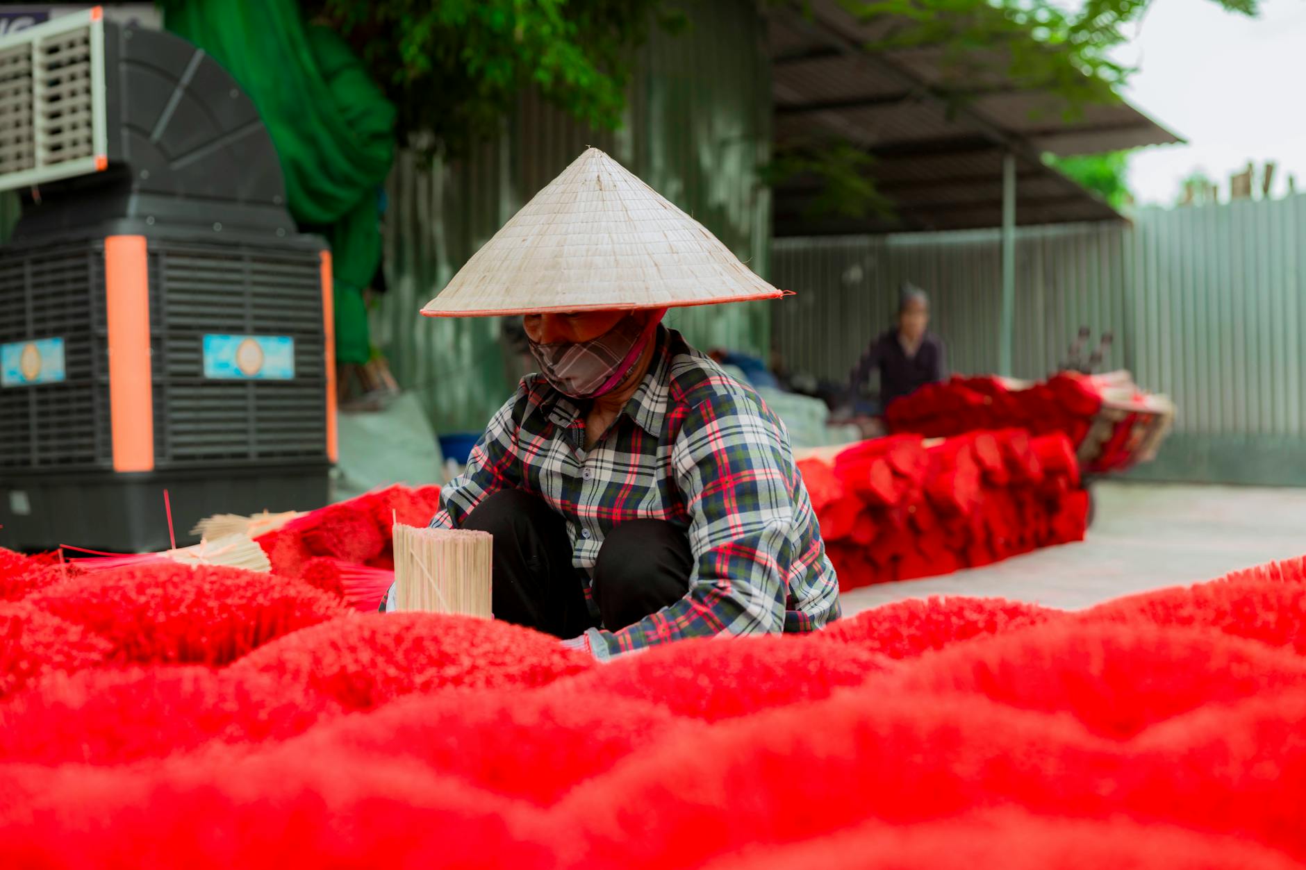 Close-up of a Vietnamese worker making red incense outdoors using traditional methods.