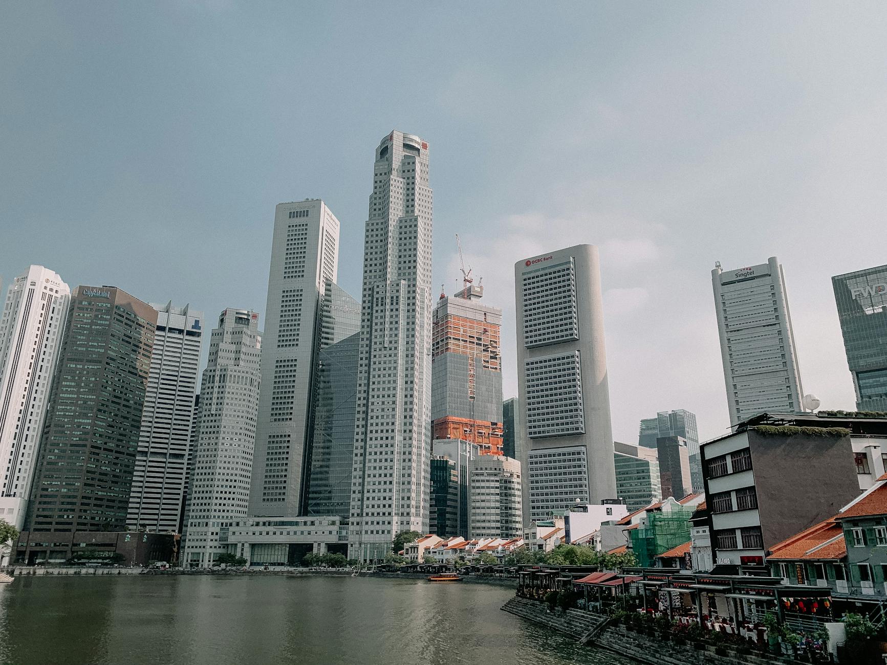 From below of towers located near calm pond in office district of contemporary city of Singapore